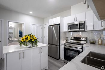 A modern kitchen with white cabinets and stainless steel appliances.
